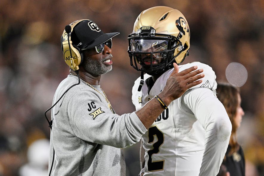 Deion Sanders, left, talks with quarterback Shedeur Sanders