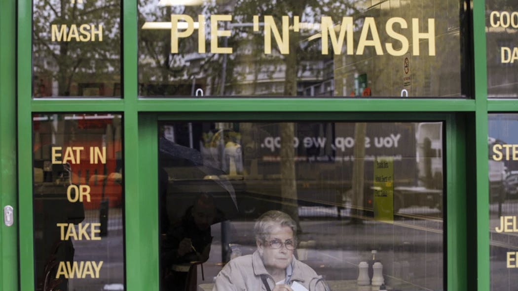 Woman sits at London pie eatery.